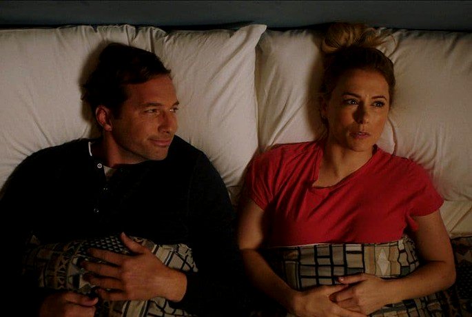 Pareja acostada en la cama; con una expresión preocupada mientras la miraba.