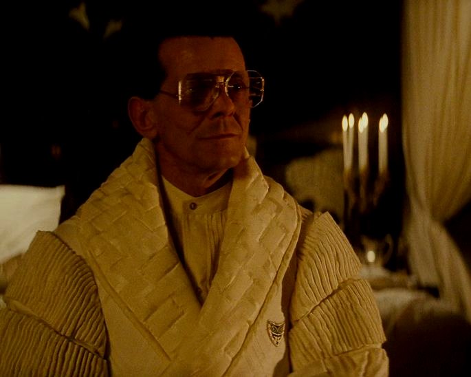 Una escena amarilla en el corredor muestra las cuchillas de Tyrell con una túnica y velas al fondo.