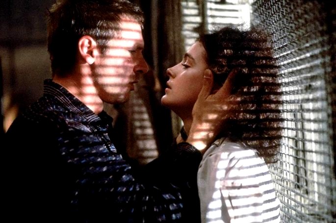 Deckar y Rachel a punto de besarse en una ventana que muestra la luz que entra por la rejilla