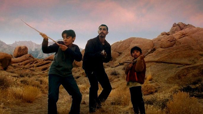 Un hombre y dos niños en un lugar abandonado, defendiéndose con palos en las manos.