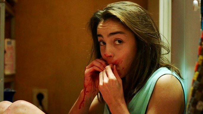 Una mujer con sangre en la boca y las manos.
