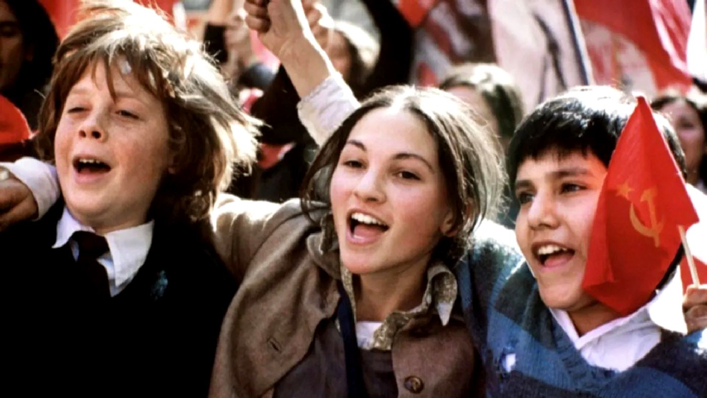 Una escena de la película Machuca muestra a tres niños abrazándose y sonriendo