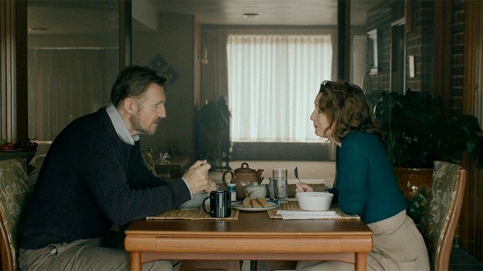 una pareja sentada en una mesa, desayunando, cara a cara.