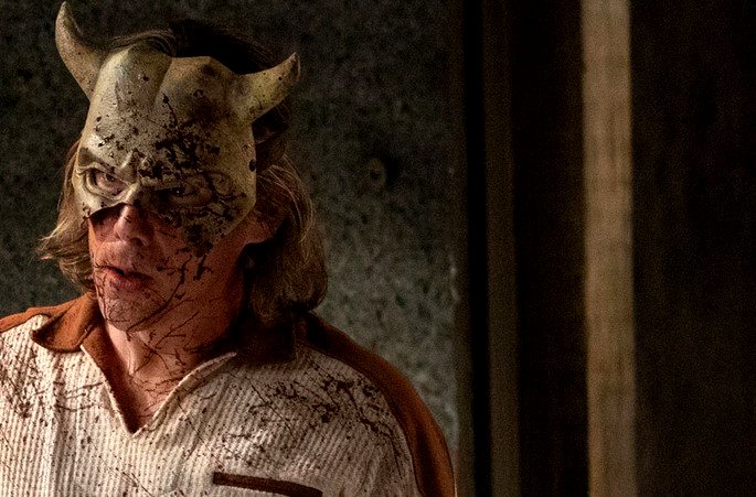 Un hombre manchado de sangre, con una máscara de diablo.