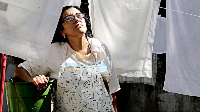 Mujer de blanco mirando sábanas secándose en la línea