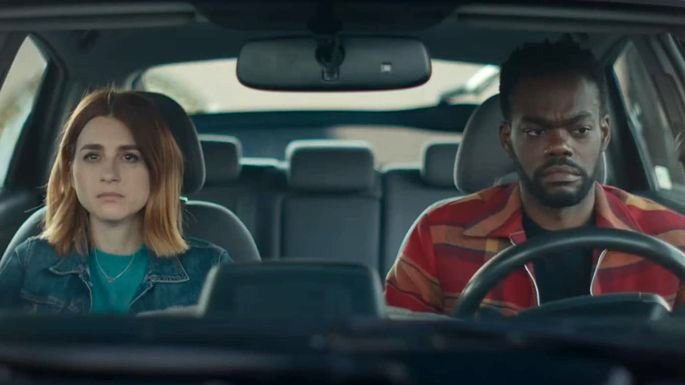 Un hombre y una mujer en un auto, con expresión triste.