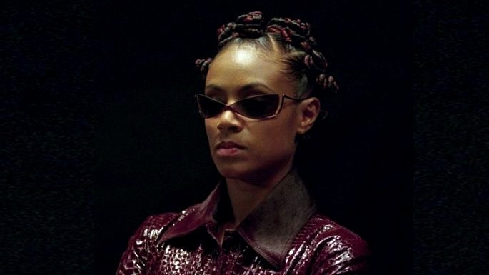 Una mujer negra con gafas de sol y un abrigo de cuero rojo.