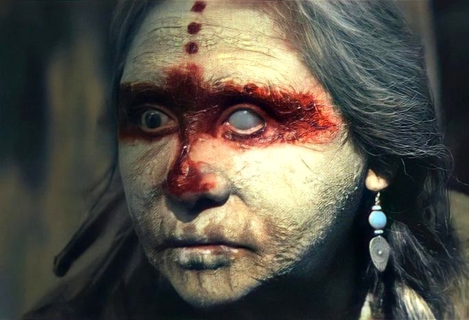 Una mujer nativa mayor con la cara pintada y una expresión aterradora.