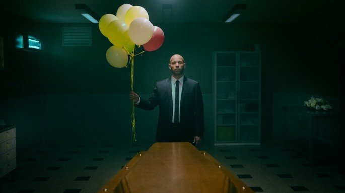 Un hombre frente a una mesa, que tiene un montón de globos.