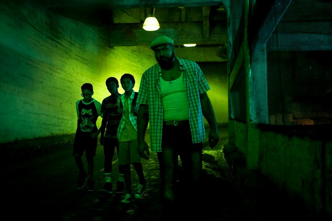 Hombre y niños en una habitación verde, como si estuvieran espiando algo.