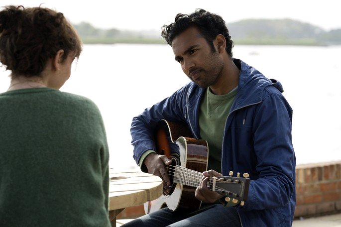 Un hombre cantándole a una mujer frente a la playa.